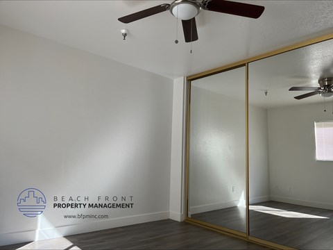 an empty room with a mirror and a ceiling fan